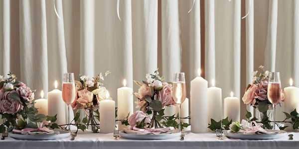 A dining table decorated for a wedding dinner with candles and flowers.
